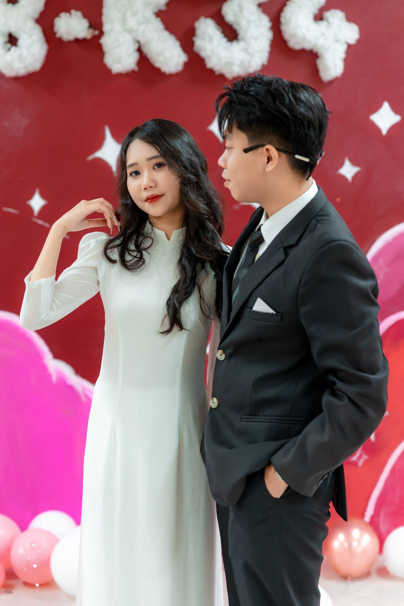 Couple posing for the camera in front of a decorated balloon photo booth backdrop