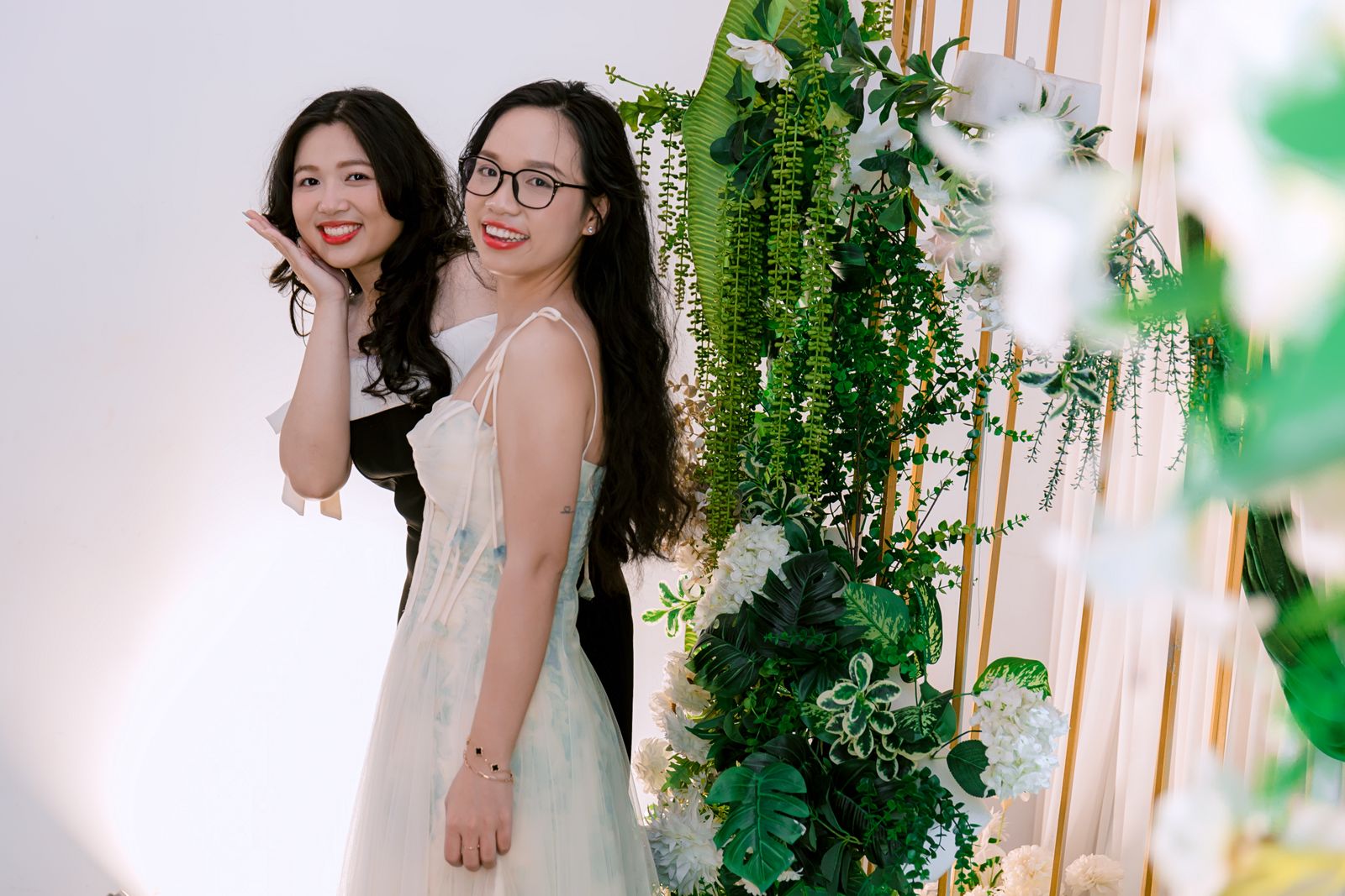 Friends posing beside a floral wall photo booth backdrop