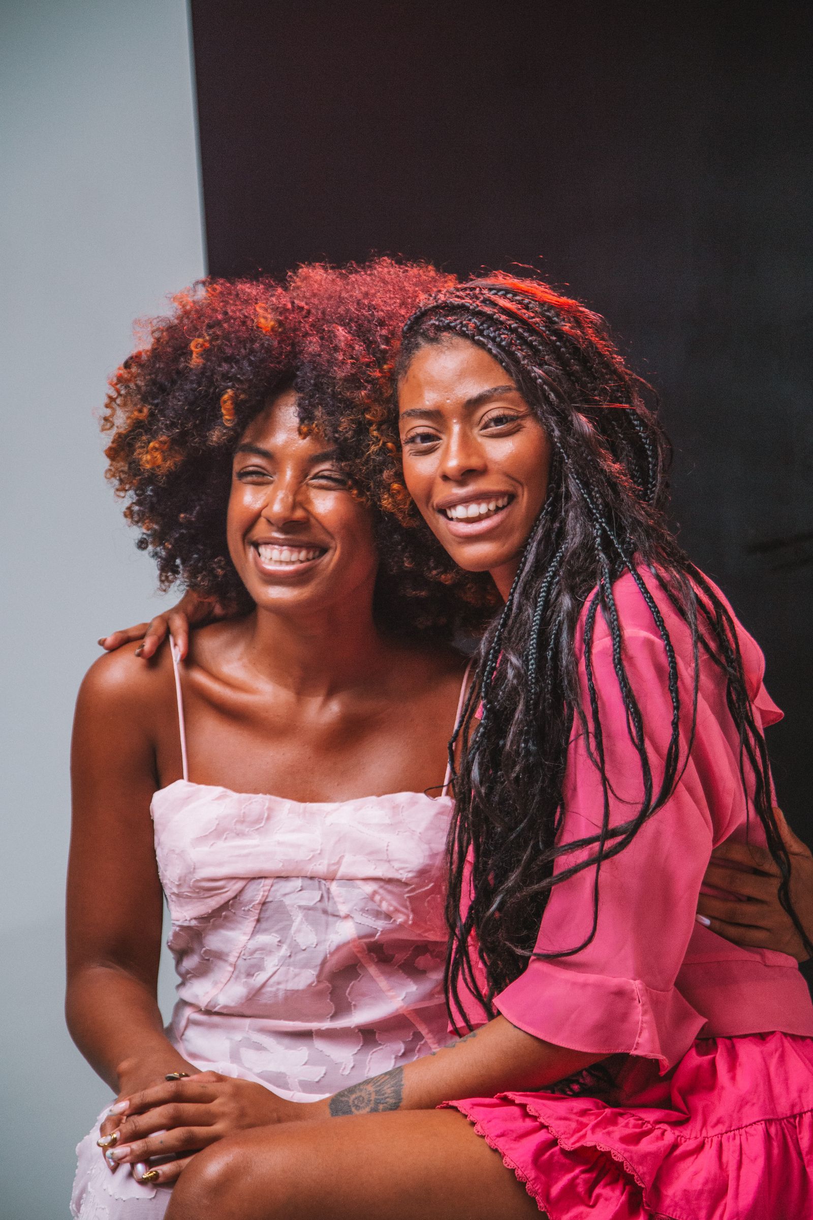 Two friends smiling together for a photo booth portrait against a plain backdrop
