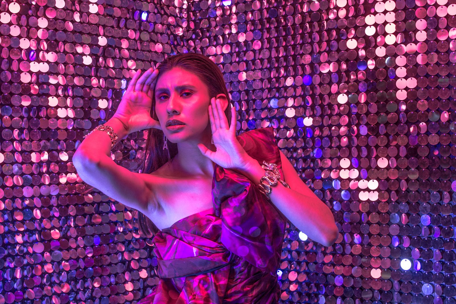Guest posing playfully against a shimmering sequin photo booth backdrop