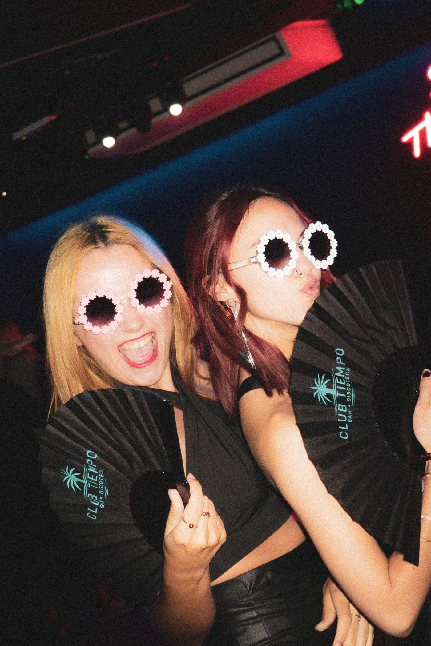Friends posing with novelty glasses and props under neon lighting